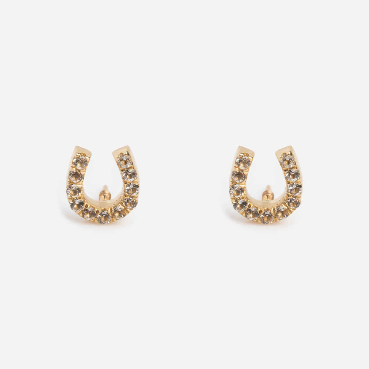 The Solid Gold Horseshoe Flat Back Studs are adorned with small, round brown gemstones and are displayed on a plain white background.