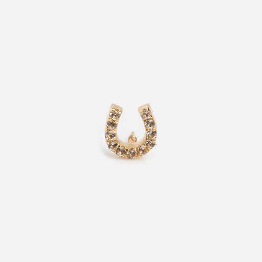 The Solid Gold Flat Back Studs feature a horseshoe shape, crafted from 9k gold and adorned with sparkling gemstones. Displayed on a plain white background, these studs offer comfortable wear and timeless elegance.