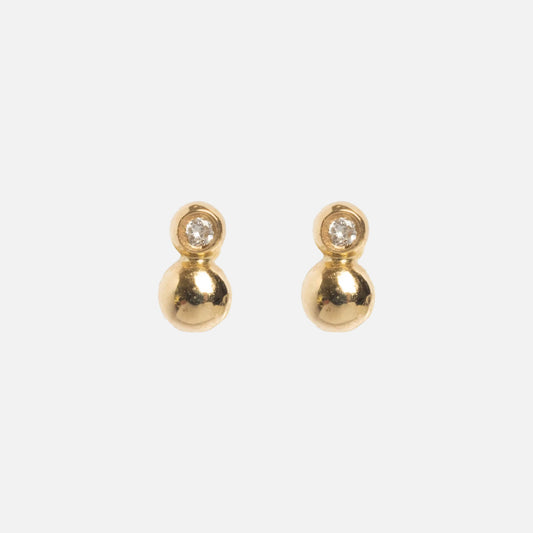 The Solid Gold Diamond Dawn Ball Studs are delicate earrings in solid gold, each with a round gold bead beneath a sparkling diamond, displayed on a plain white background.