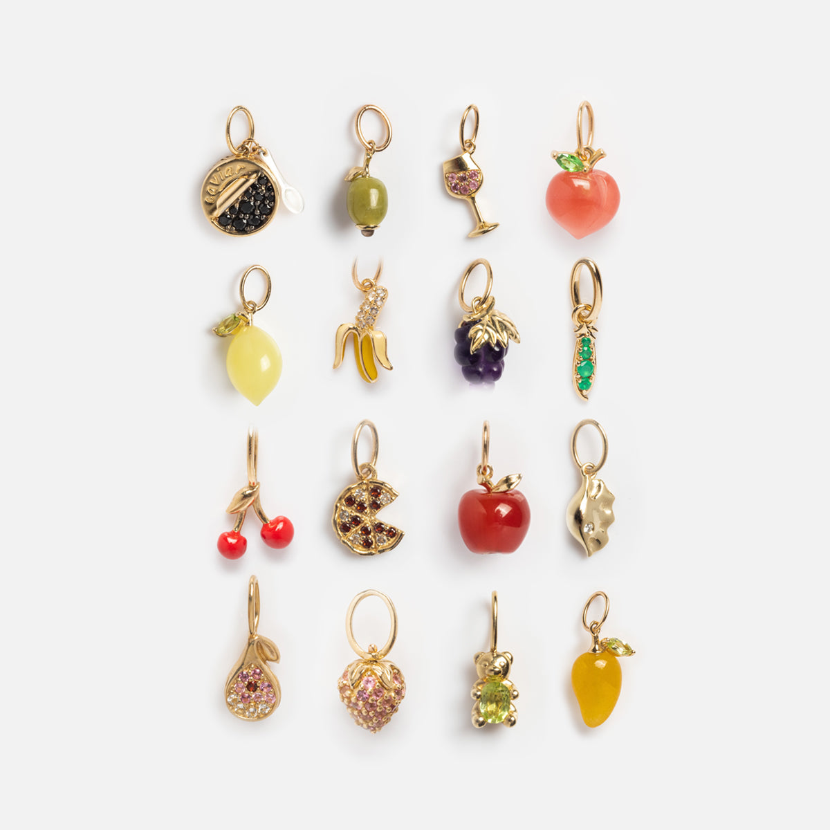 The Solid Gold Foodie Charm set features fifteen colorful, gold-accented charms shaped like fruits, a wine glass, and a bear, all playfully arranged in a grid against a white background—ideal for charm necklaces.