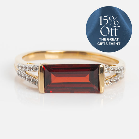 The 14k Gilded Garnet East West Baguette Ring features a rectangular red garnet and small clear stones on a solid gold band, shown on a white surface. A blue label reads “15% Off THE GREAT GIFTS EVENT at Local Eclectic.”.
