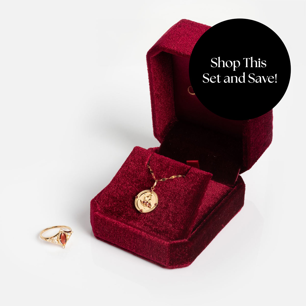 The Solid Gold 2026 January Garnet Capsule Set with Free Gift features a garnet ring and gold pendant in a red velvet box. A black circle overlay says: Shop This Set and Save!.