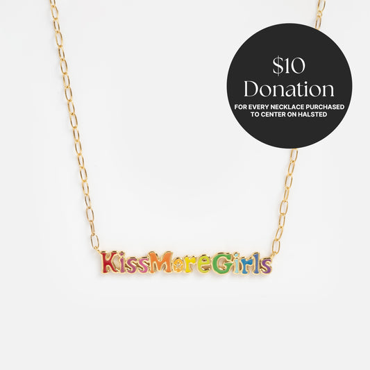 The Kiss More Girls Necklace features a gold chain and colorful pendant with "Kiss More Girls." With each purchase, a $10 donation is made to Center on Halsted.