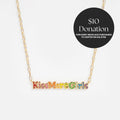 The Kiss More Girls Necklace features a gold chain and colorful pendant with 