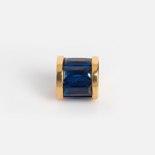 Charms by Thatch features a gold-plated cylindrical charm with a large rectangular blue gemstone at its center, displayed on a white background—ideal for personalizing your necklace.