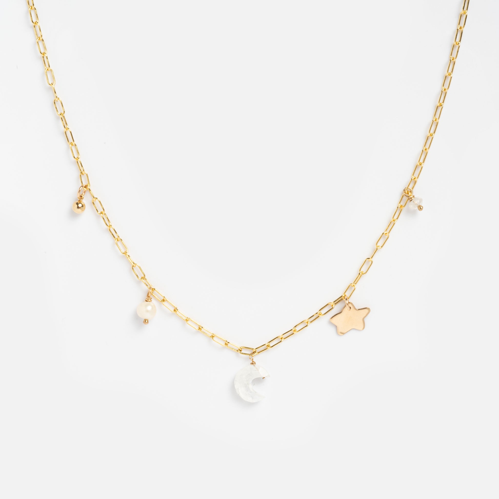 The Celine Charm Necklace Sample features a delicate 14k gold-filled chain with brass charms—a crescent moon, star, plus small pearls and moonstone pearl beads—displayed on a white background.