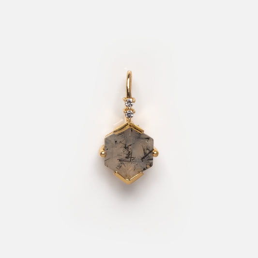 The Solid Gold Amulet Charm is a hexagonal pendant necklace featuring a gray gemstone with black inclusions and three white accent stones, exclusively from Local Eclectic, showcased on a plain white background.