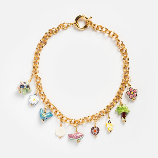 The Good Idea Necklace pairs perfectly with a gold chain bracelet featuring eight colorful enamel charms—starfish, clock, bird, flower, sneaker, heart, candy, and leaf—for a playful yet elegant look on a white background.