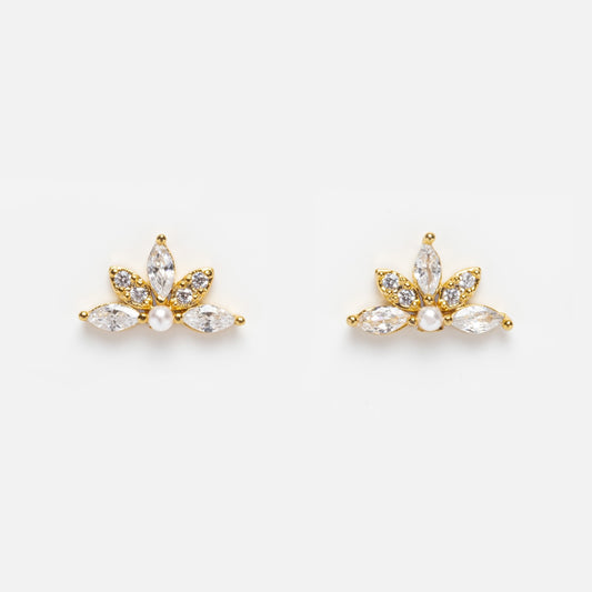 The Harlowe Studs are flower-shaped earrings with marquise-cut clear petals, a faux pearl center, and crystals on three petals. Finished in 14k yellow gold plating, they are shown against a white background.