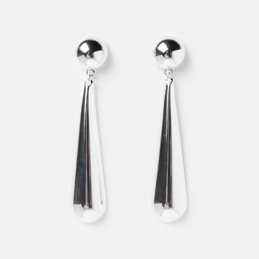 The Linnea Earrings feature shiny silver plating, round studs, and long teardrop-shaped dangles—an eye-catching accessory perfect for bold style statements. Displayed on a plain white background.