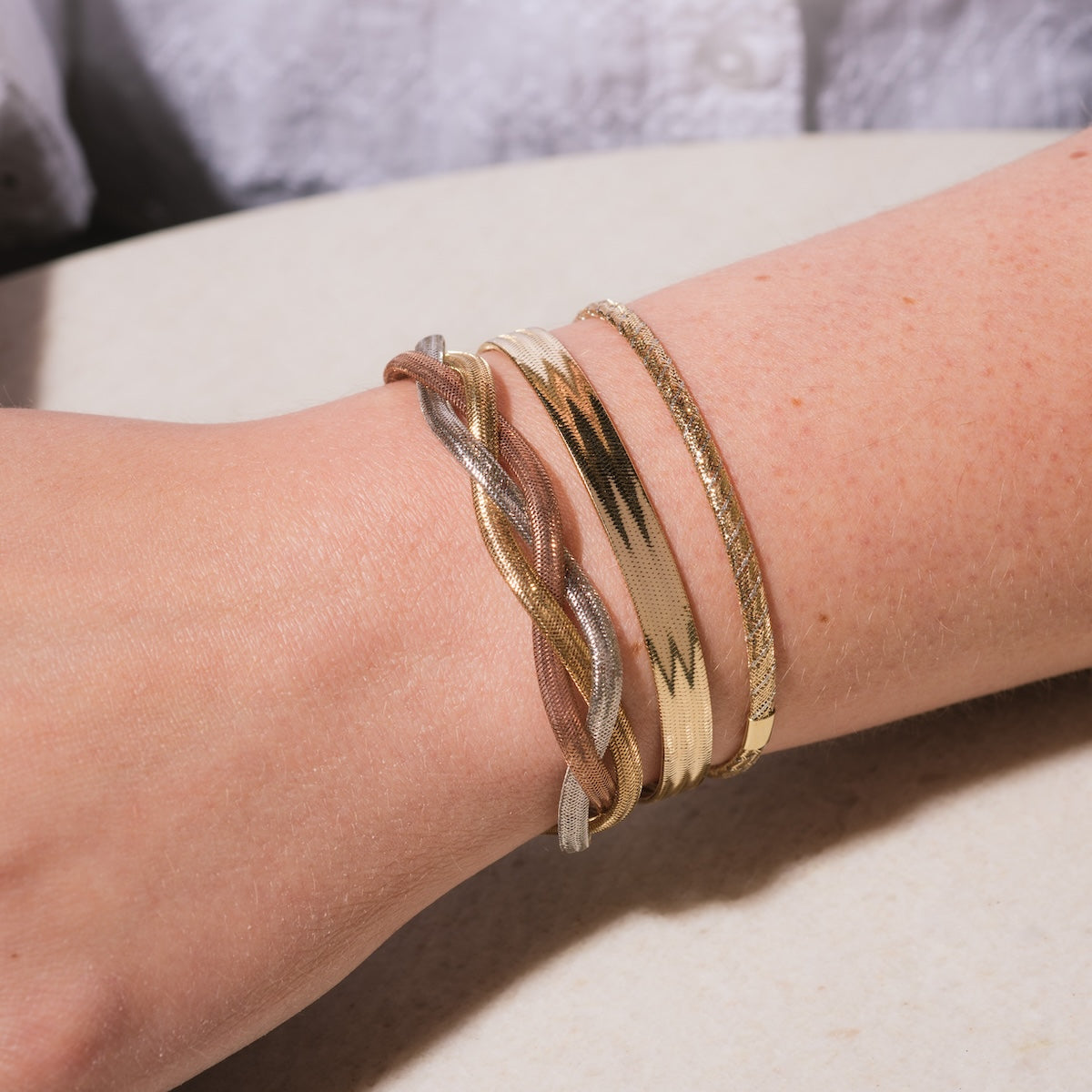 Closeup of Model wearing stack of Solid Gold Mixed Metal Mesh Bracelet, Solid Gold Mixed Metal Braided Mesh Bracelet, and Solid Gold Bold Mesh Bracelet
