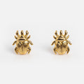 Beetle Studs are 14k gold plated earrings shaped like scarab beetles, shown on a white background. These unique earrings bring elegance and intrigue to any outfit.