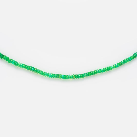 The Beaded Gemstone Necklace Bright Green Opal Sample features a single strand of small, round, bright green beads arranged in a gentle curve against a plain white background.