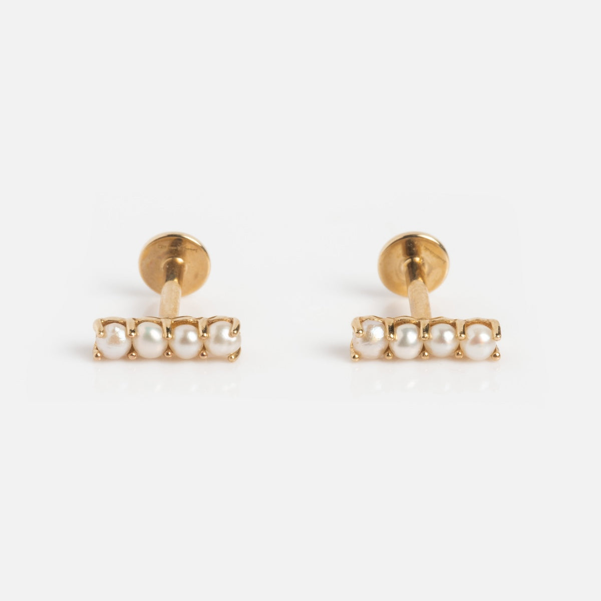 The Solid Gold Pearl Bar Flat Back Studs feature a horizontal row of four small white pearls on each earring, shown against a white background.