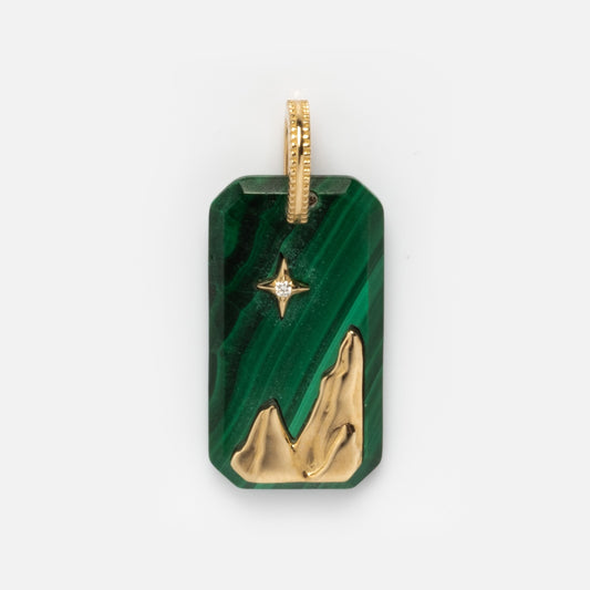 The Solid Gold Crystal Element Charm is a rectangular green natural crystal pendant with a gold mountain design at the base, a gold star and small lab-created diamond above, and a gold loop at the top for hanging.