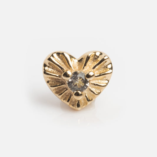 The Solid Gold Heart Flat Back Studs are small, heart-shaped earrings featuring a textured sunburst design and a clear center gemstone, shown on a white background.