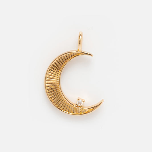 The Charms by Elizabeth Stone features a gold crescent moon pendant with engraved lines and a clear gemstone near the tip, shining in 14k gold plate and displayed on a plain white background.