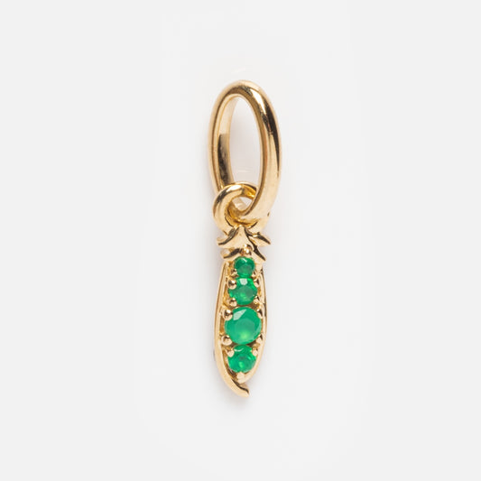 The Solid Gold Foodie Charm is a 9k yellow gold pea pod with three green gemstones in a row, attached to a gold loop for hanging. Set against a white background, it’s ideal for your fruit charm necklace collection.