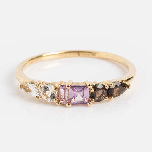 The Solid Gold Modern Ombre Birthstone Ring features five uniquely shaped gemstones in clear, purple, and brown hues, set on a delicate band against a white background.