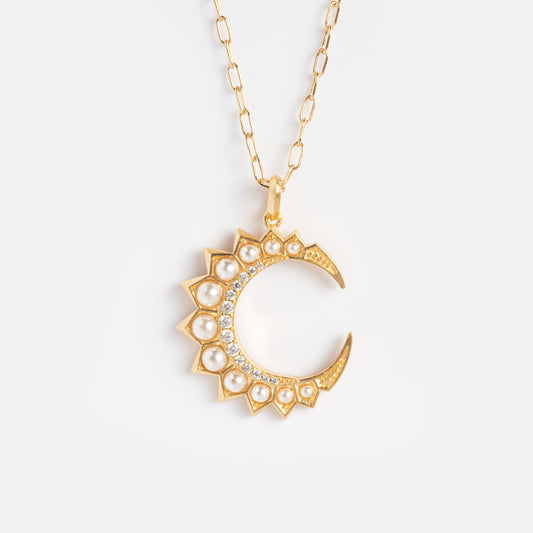 The Selene Crescent Necklace Sample features a gold-plated crescent moon pendant with pearl and cubic zirconia accents, sun-like rays along the curve, and hangs from a delicate gold chain on a white background.
