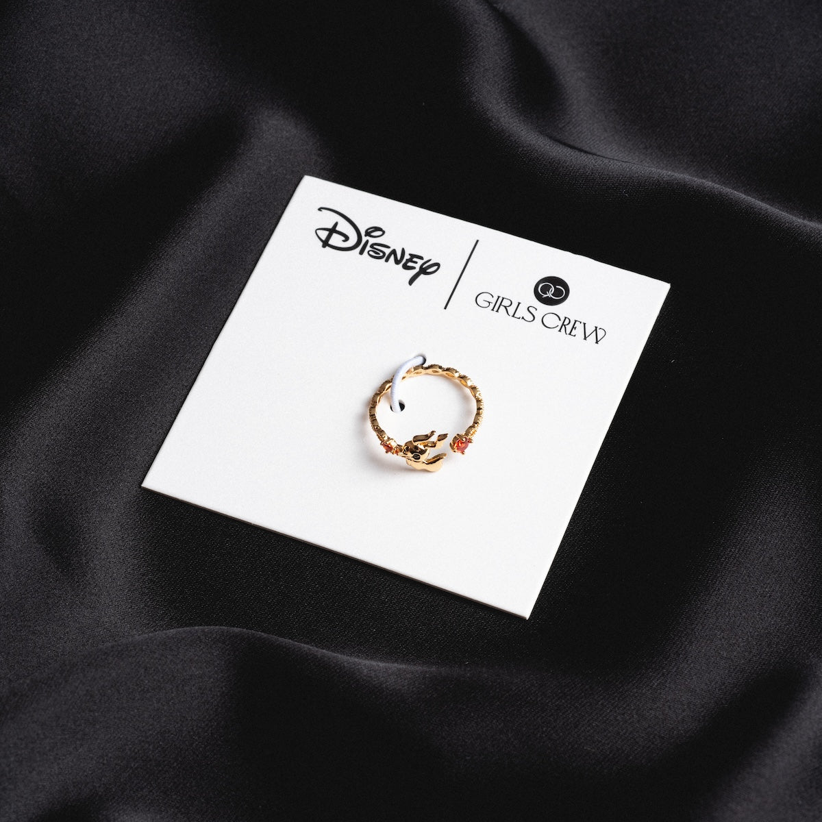 The Disney Zero Adjustable Ring, part of the Disney jewelry collection, is shown on a white card labeled Disney and Girls Crew, set against a smooth black satin background.