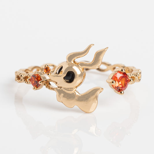 The Disney Zero Adjustable Ring Sample Size 6.5 is an 18k yellow gold plated ring featuring a whimsical ghost with black eyes, holding two orange cubic zirconia stones; ornate details and orange stones accent the band.