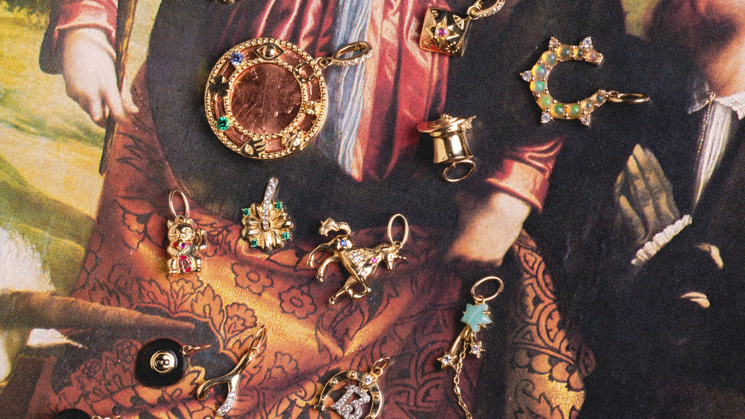 A close up of gold charms with good luck motifs laying on a colorful image of a painting