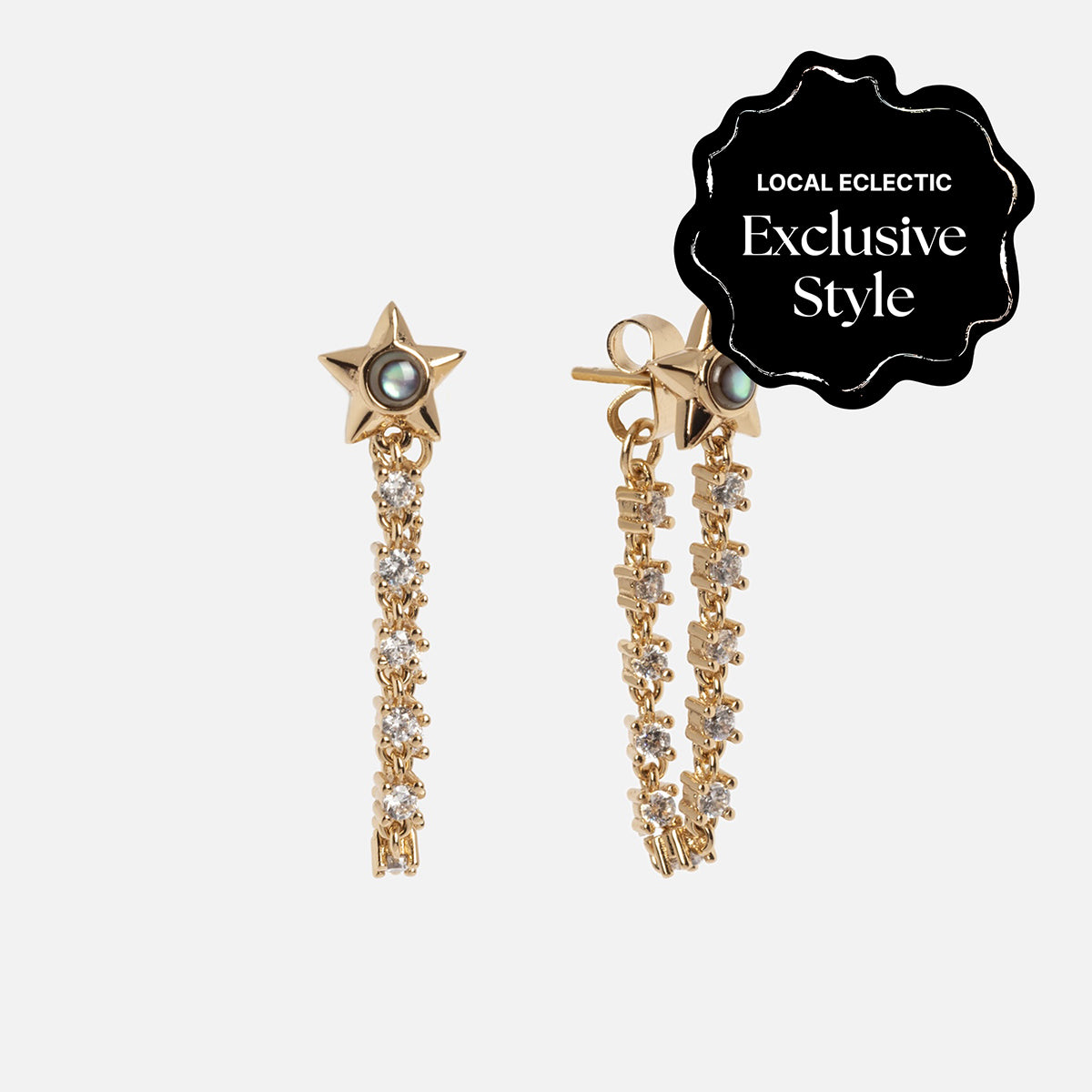The Lucky Star Tennis Chain Earrings feature gold star-shaped drops with black center stones, dangling chains adorned with clear crystals, and a 14k yellow gold plated finish. This design is a Local Eclectic exclusive.