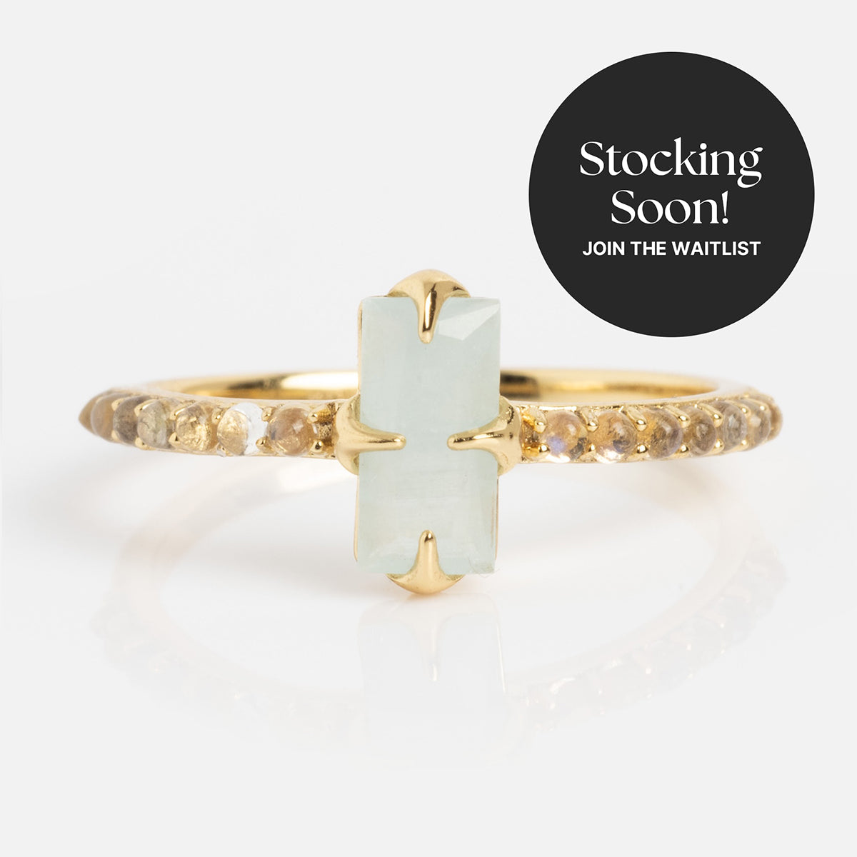2026 March Capsule Delicate Aquamarine Solitaire Ring: gold vermeil band with a rectangular aquamarine center stone and small round accents, shown on white. A black circle reads Stocking Soon! Join the Waitlist.