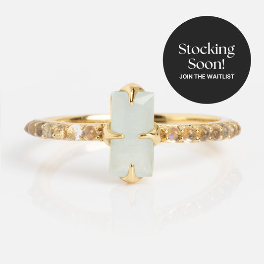 2026 March Capsule Delicate Aquamarine Solitaire Ring: gold vermeil band with a rectangular aquamarine center stone and small round accents, shown on white. A black circle reads Stocking Soon! Join the Waitlist.