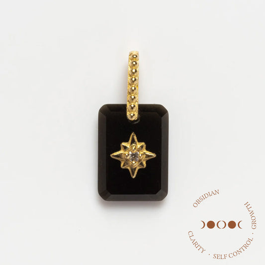 The Solid Gold Crystal Amulet Charm for Manifestation is a rectangular black obsidian pendant with a gold star, embedded stone, and textured gold bail. It features Obsidian, Clarity, Self Control, Growth and a lunar phase graphic on the front.