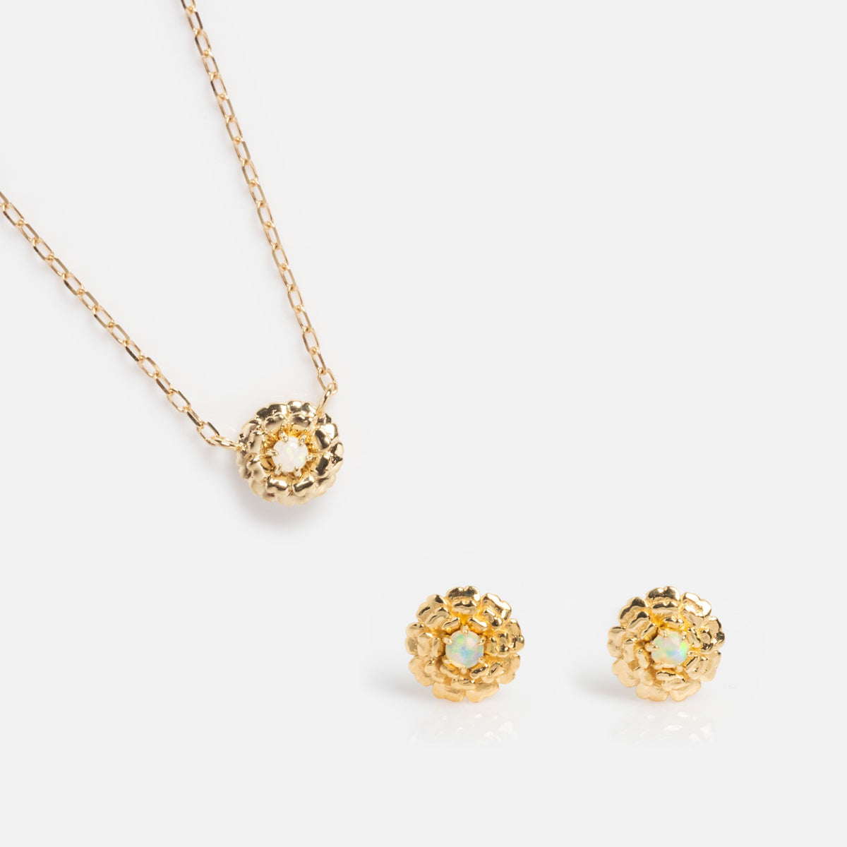 The Solid Gold Birth Flower Gift Set features a birthstone necklace and matching stud earrings with a delicate flower design and opal-like center, presented on a plain white background—an ideal birth flower gift.