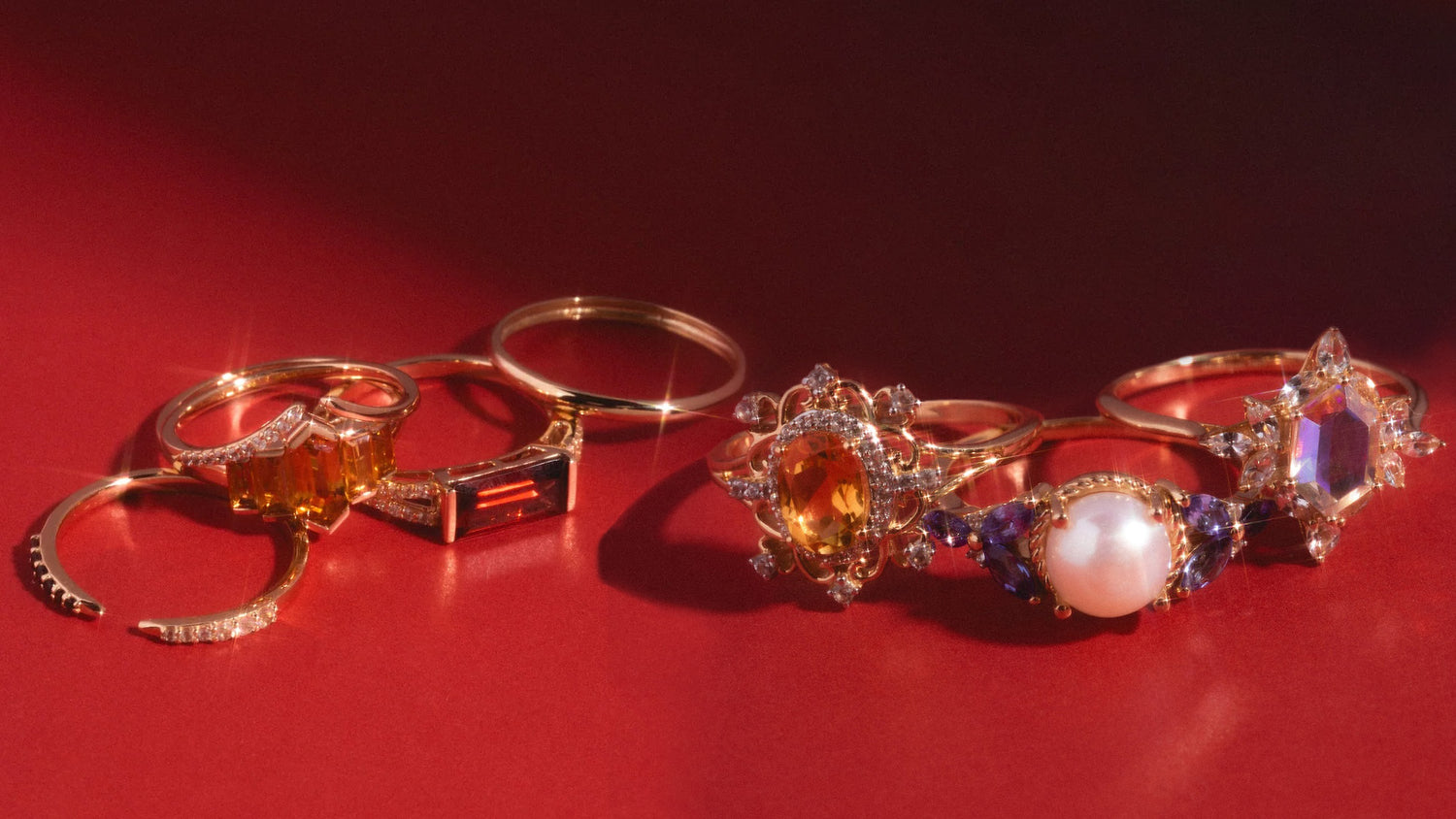 Close up of six gold gemstone rings laying on a red surface