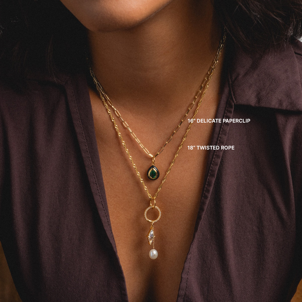 A person in a dark, open-collared shirt models Chain For Charms: a layered look featuring a 16-inch delicate paperclip chain with teardrop pendant and an 18-inch gold plated chain accented by a pearl and crystal drop.