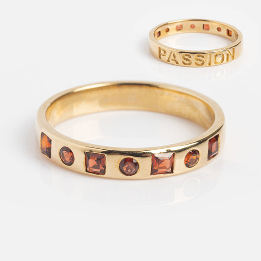 The Solid Gold Within You Birthstone Band Sample Size 7 features a gold ring with natural red stones and a 9k yellow gold PASSION-engraved band, each 3.1 mm wide, shown on a white background.