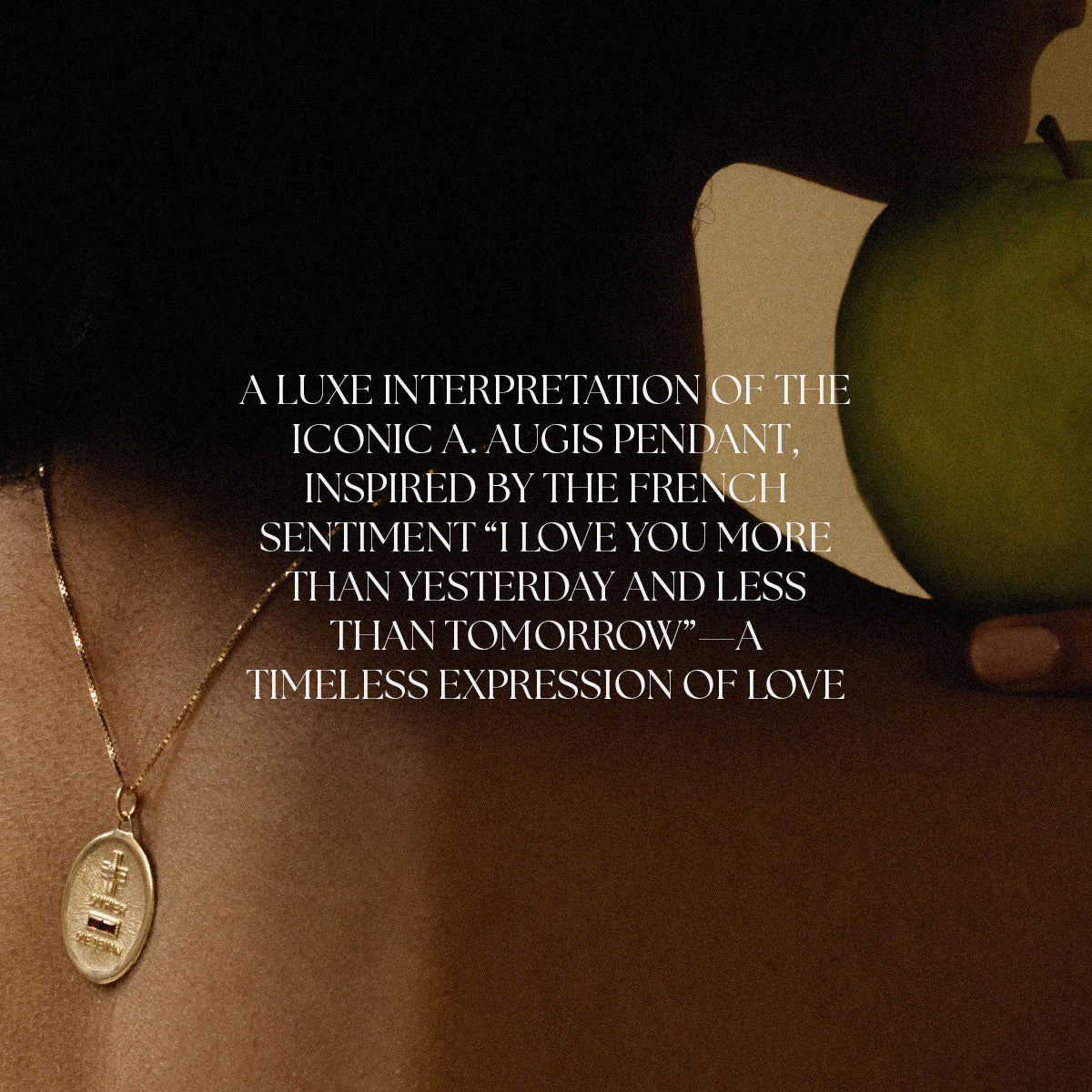 A close-up of a woman’s neck wearing the 14k Vintage Revival Qu’hier Que Demain Pendant Charm, holding a green apple. Overlay text highlights its luxe design inspired by “I love you more than yesterday and less than tomorrow.”.