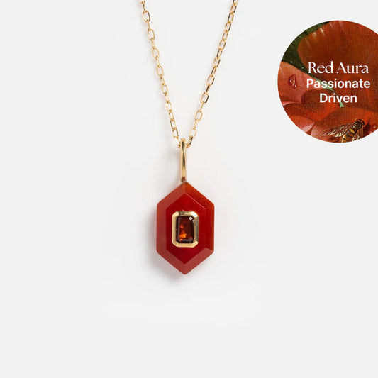The Solid Gold Aura Necklace showcases a red hexagonal pendant with a rectangular gemstone. The inset reads: “Red Aura, Passionate, Driven” on a vibrant red floral background—an ideal statement piece.