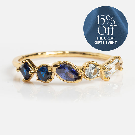 The Shades of You Ombre Birthstone Ring, plated in 14k yellow gold and set with five assorted blue and clear gemstones, is shown on a white surface. A circular blue label at the top right says: 15% Off THE GREAT GIFTS EVENT.