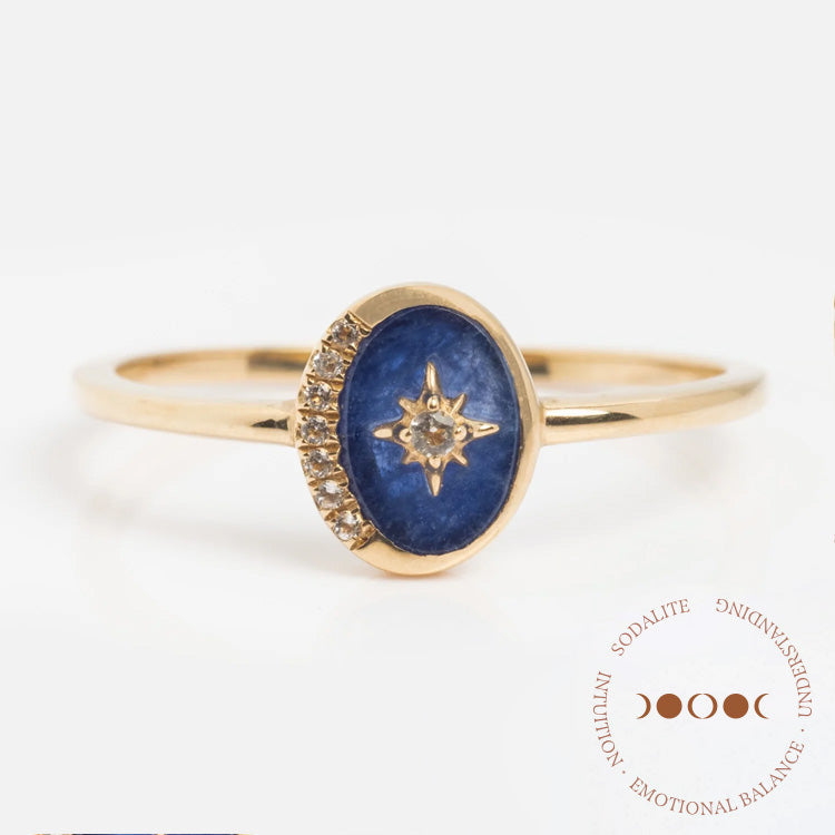 The Solid Gold Crystal Crescent Moon Ring for Manifestation features an oval blue sodalite stone with a starburst design, tiny diamond crescent accents, and “Sodalite, Intuition, Emotional Balance, Understanding” in circular text.