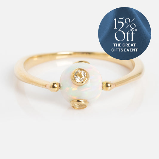 The Solid Gold Gem Drop Opal Spinner Ring features a central round opal and two small diamonds, displayed on a white background. A blue circle at the top right reads, "15% Off THE GREAT GIFTS EVENT.
