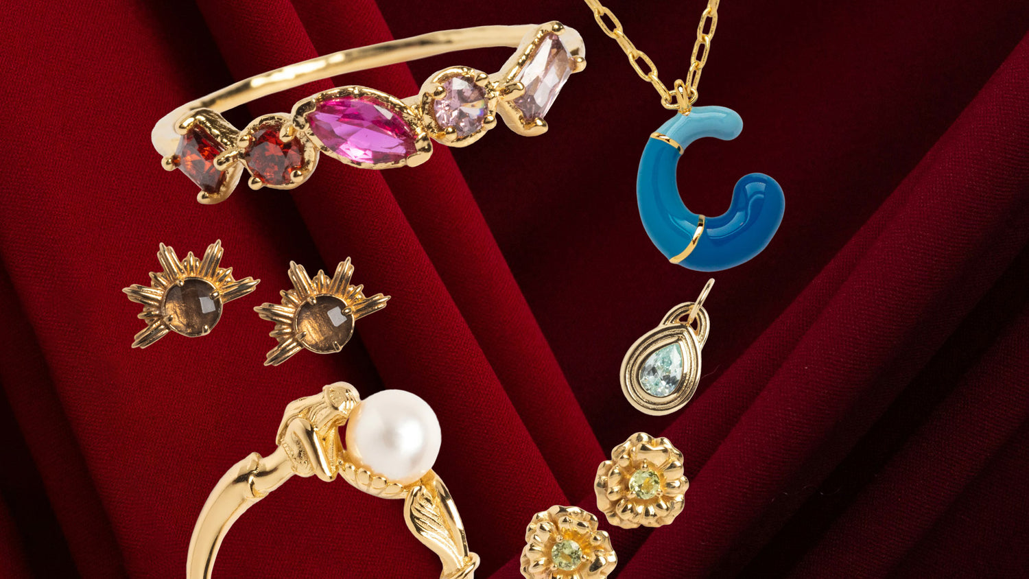 Gold jewelry set with colorful gemstones on a red background