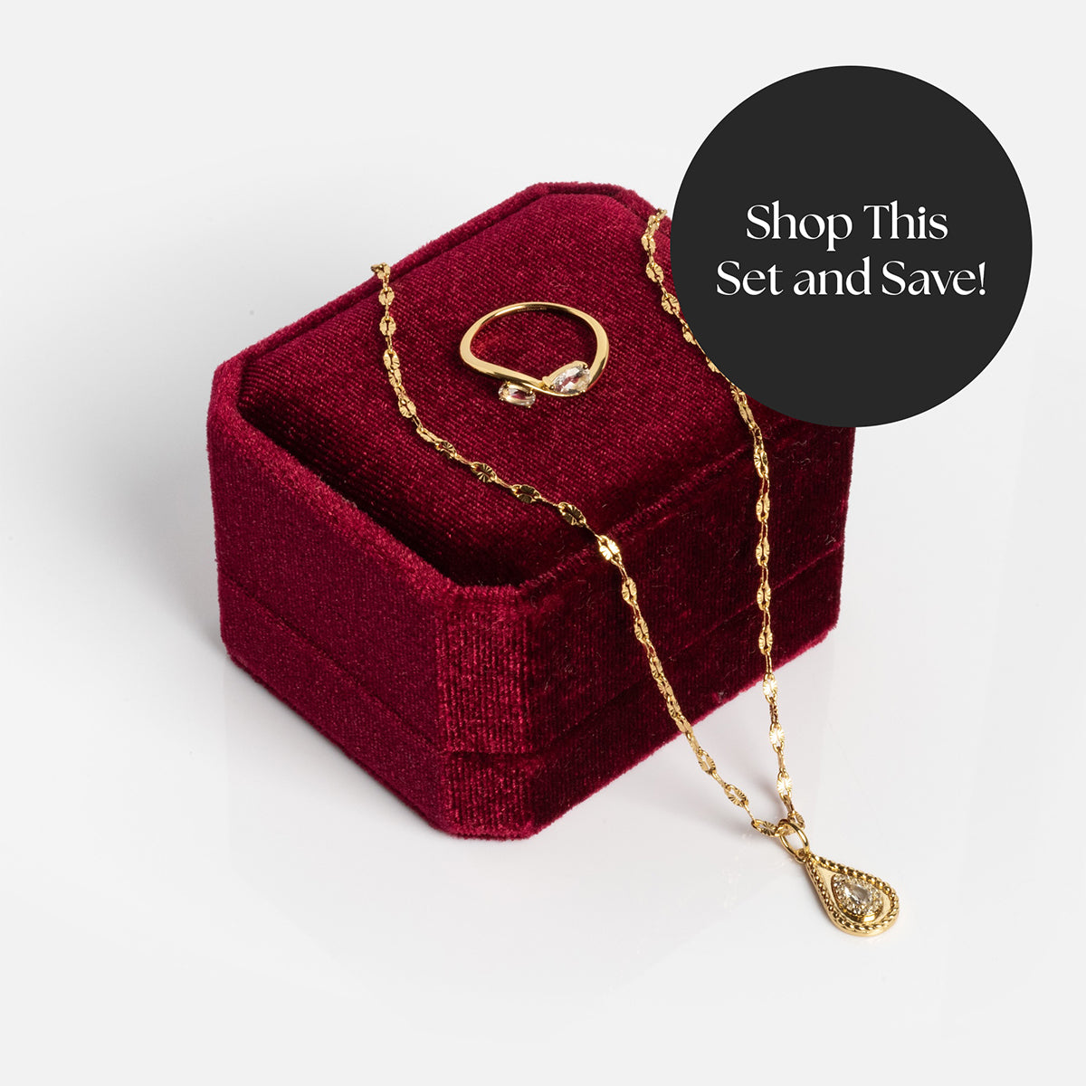 The 2026 April White Topaz Capsule Set with Free Gift, featuring a gold vermeil ring and teardrop pendant necklace, is displayed on and beside a red velvet jewelry box. A black circle reads, Shop This Set and Save!.
