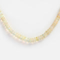 Close-up of the Beaded Gemstone Necklace, featuring small, round, translucent beads with a subtle iridescent sheen, beautifully arranged in a gentle curve on a white background.