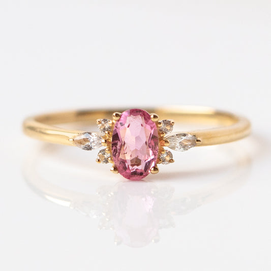 The 14k Pink Tourmaline and White Sapphire Ring Sample Size 7 features an oval pink tourmaline with marquise and round white sapphires on each side, crafted in recycled solid yellow gold and shown on a white background.