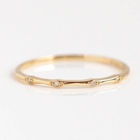 The Classic Solid Gold Jewelry Starter Set features a delicate ring with a thin solid gold band accented by small, evenly spaced diamonds, showcased on a white background.