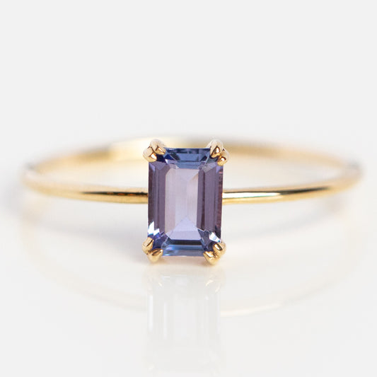 The Solid Gold Essential Baguette Birthstone Ring features a rectangular, faceted lavender gemstone in a four-prong setting, displayed on a white background.