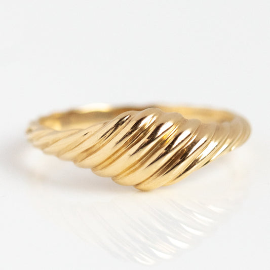 The Solid Gold Twisted Signet Ring, crafted in 9k gold with a smooth, twisted ribbed design and vintage inspiration, is displayed on a white reflective surface.