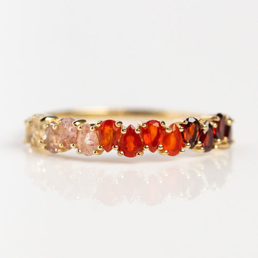 The Solid Gold Ombre Birthstone Ring Garnet Sample is crafted in 9k yellow gold and features natural gems that gradient from pale pink to vibrant orange to deep red, shown on a white background.