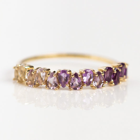The Solid Gold Ombre Birthstone Ring Amethyst Sample features a row of oval and pear-shaped natural gems in purple and light pink hues, set in 9k solid yellow gold, shown against a white background.