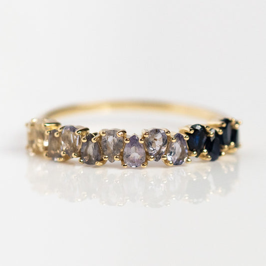 The Solid Gold Ombre Birthstone Ring Blue Sapphire Sample features a delicate 9k yellow gold band set with oval natural gems that transition from pale blue to deep sapphire and black.